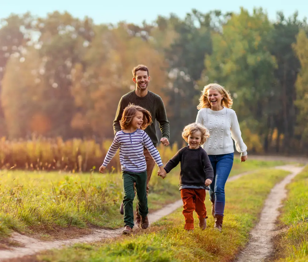 A family of four hikes a trail in a green landscape.