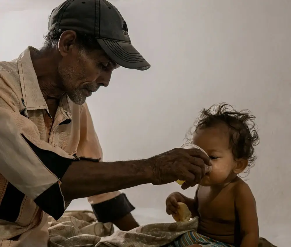 A father gives his child a drink